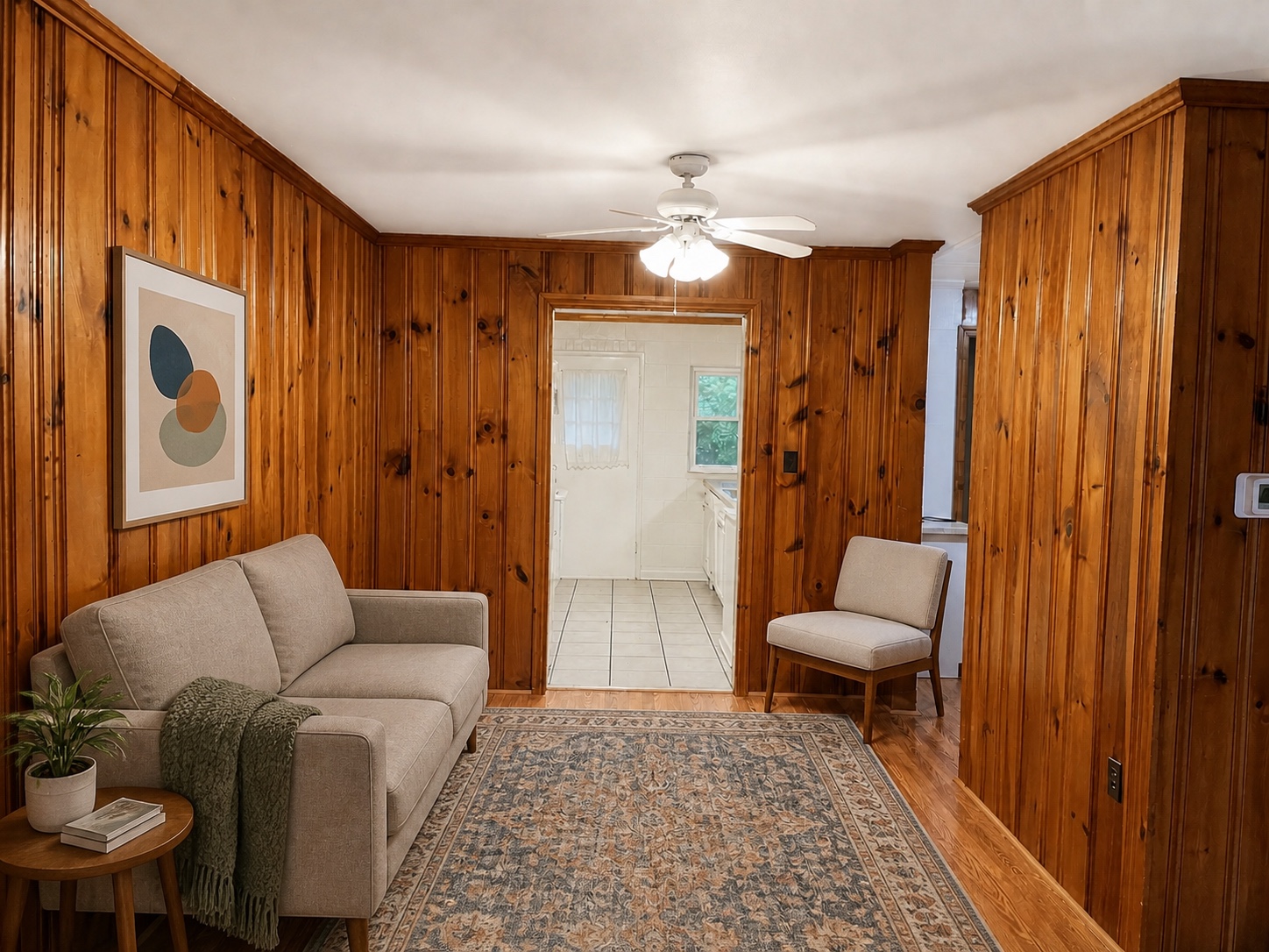 Living room with warm knotty-pine paneling opening into the kitchen
