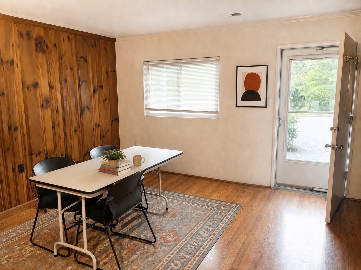 Dining area with wood-accent wall, large window, and glass front door