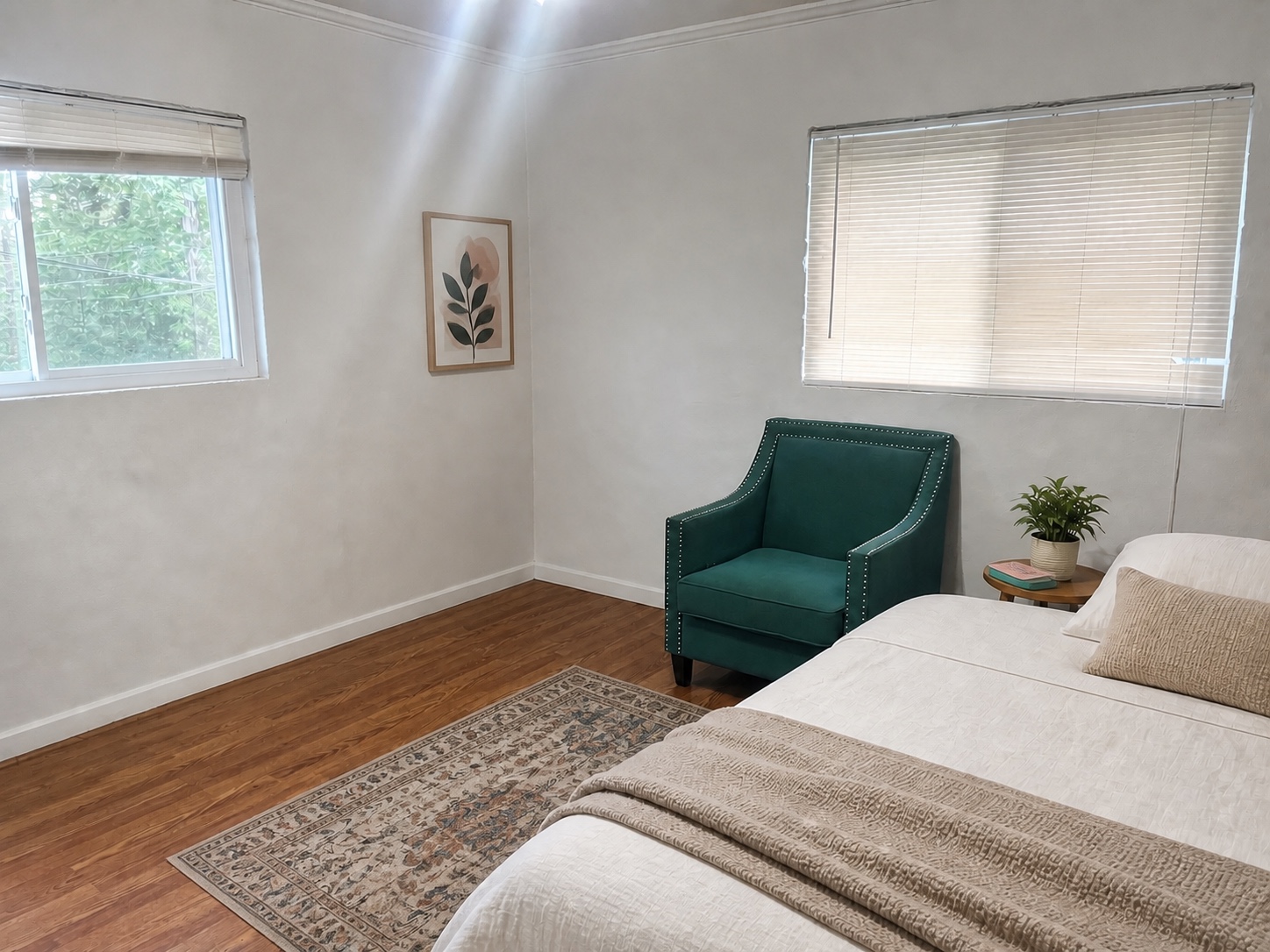 Spacious primary bedroom with two windows and hardwood-style flooring