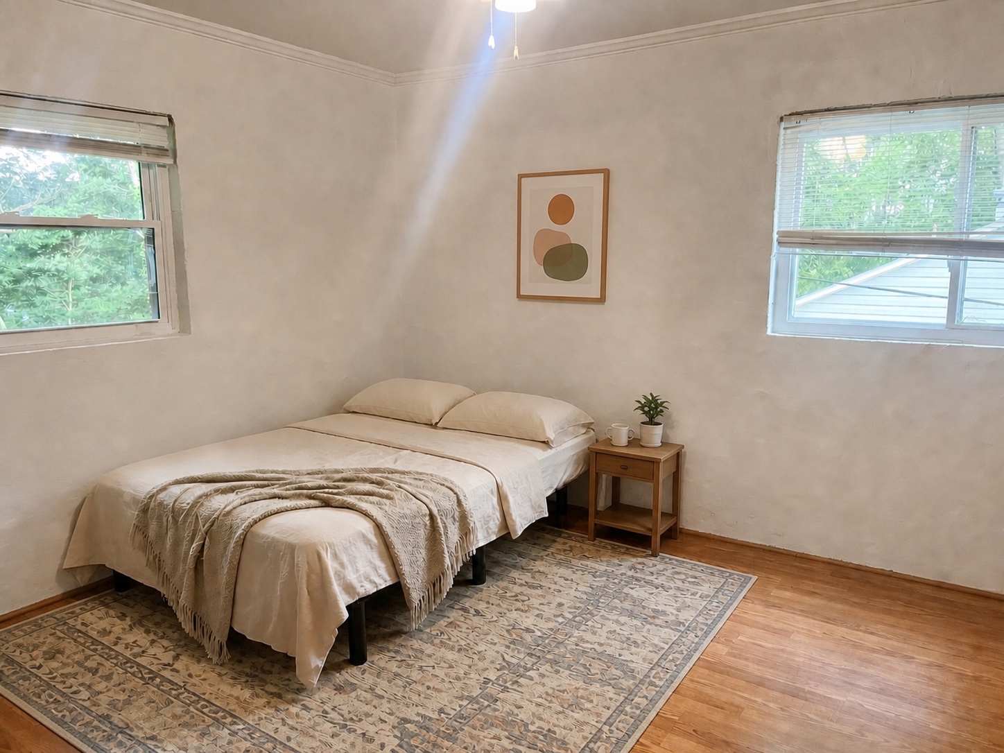 Bright second bedroom with corner windows and ceiling fan