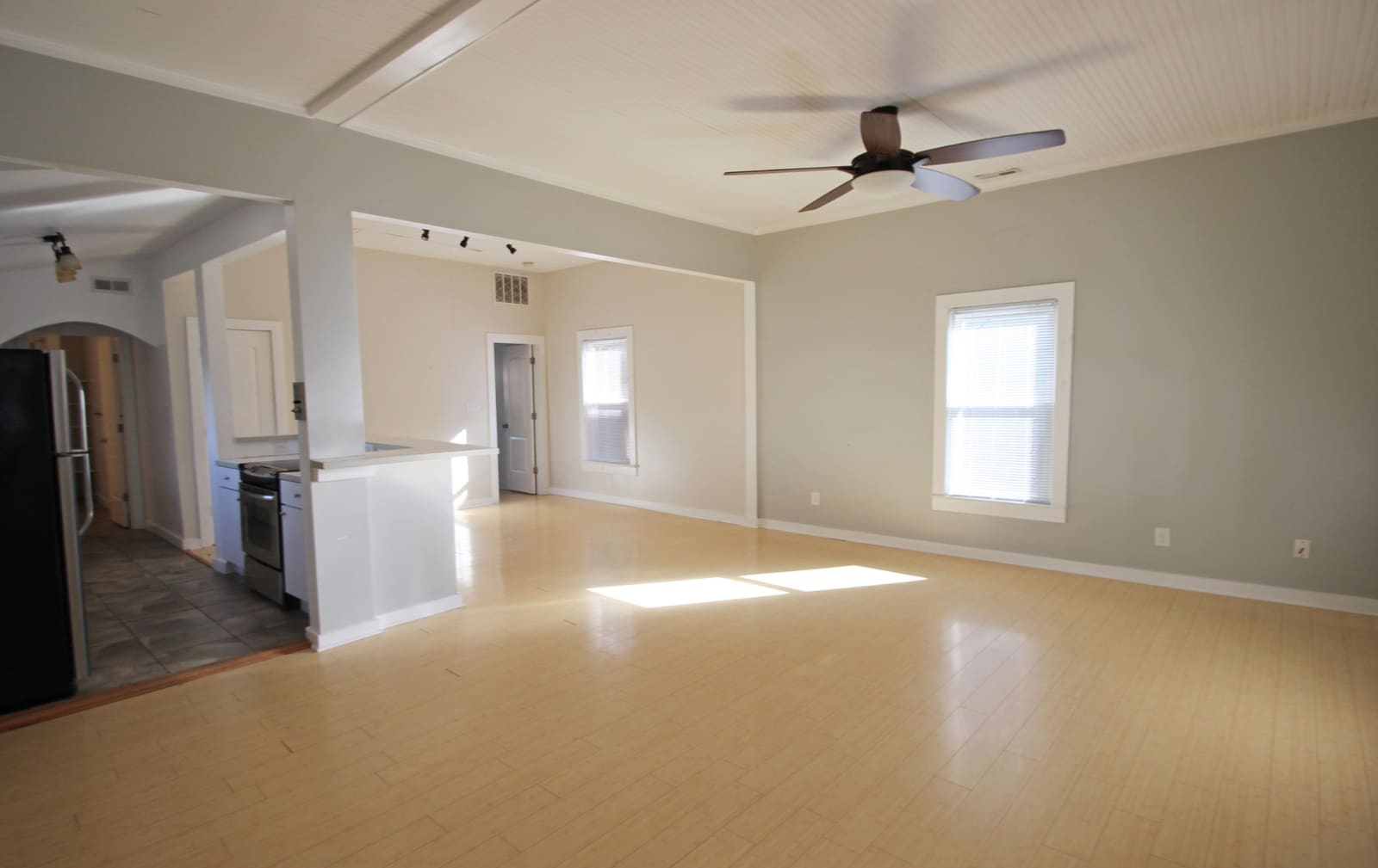Open living room with vaulted beadboard ceiling, ceiling fan, and bamboo floors