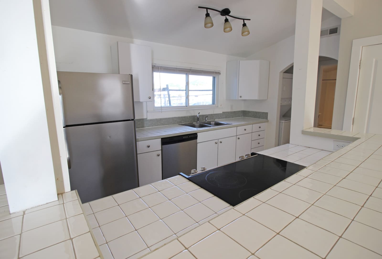 Open kitchen with tile counters, stainless appliances, and breakfast-bar cooktop
