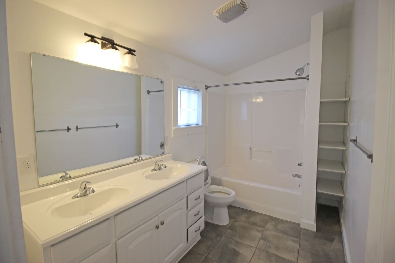 Bathroom with double-sink vanity, tub and shower, and built-in shelving