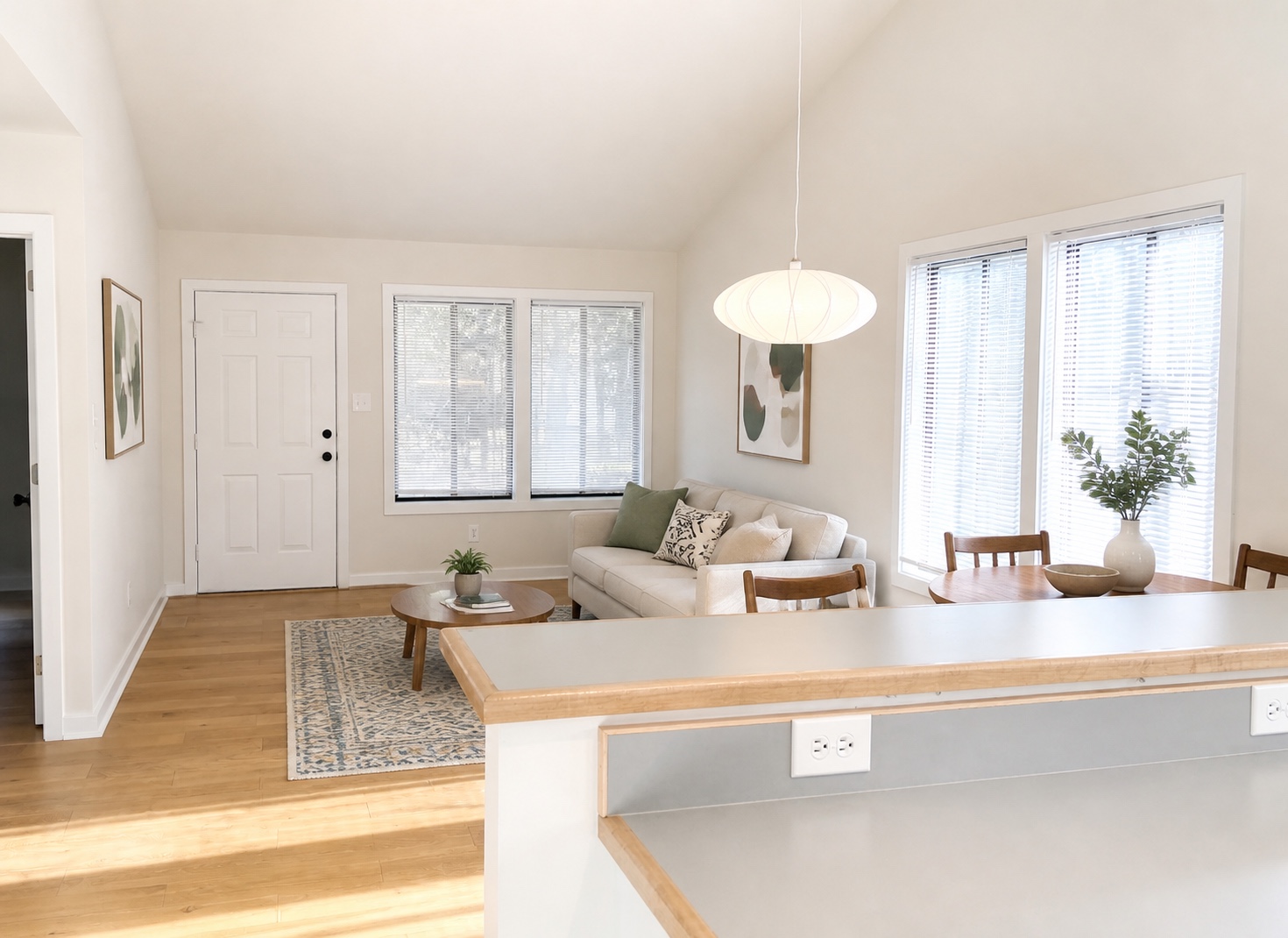 Living and dining area with large windows, front entry, and breakfast bar (similar unit shown)