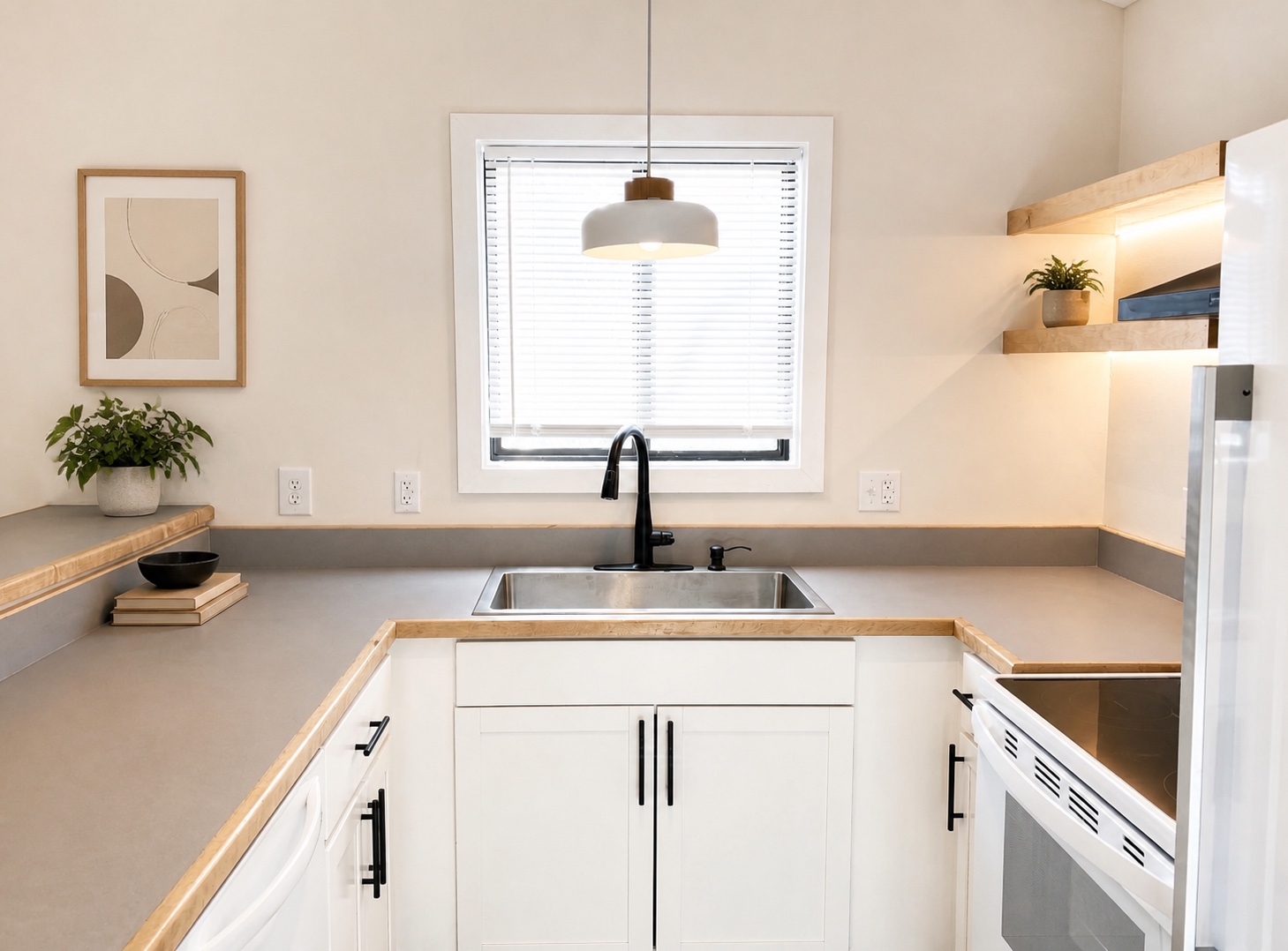 Kitchen sink under a bright window with matte-black faucet and pendant light (similar unit shown)