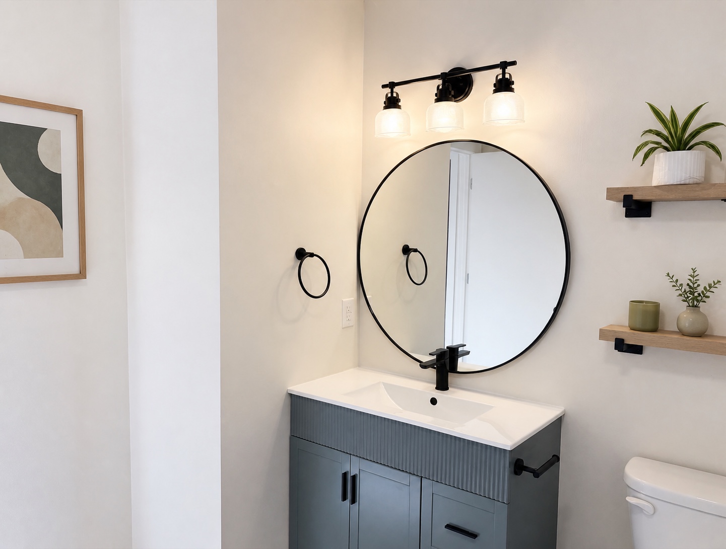 Bathroom vanity with round mirror, matte-black fixtures, and wood shelving (similar unit shown)